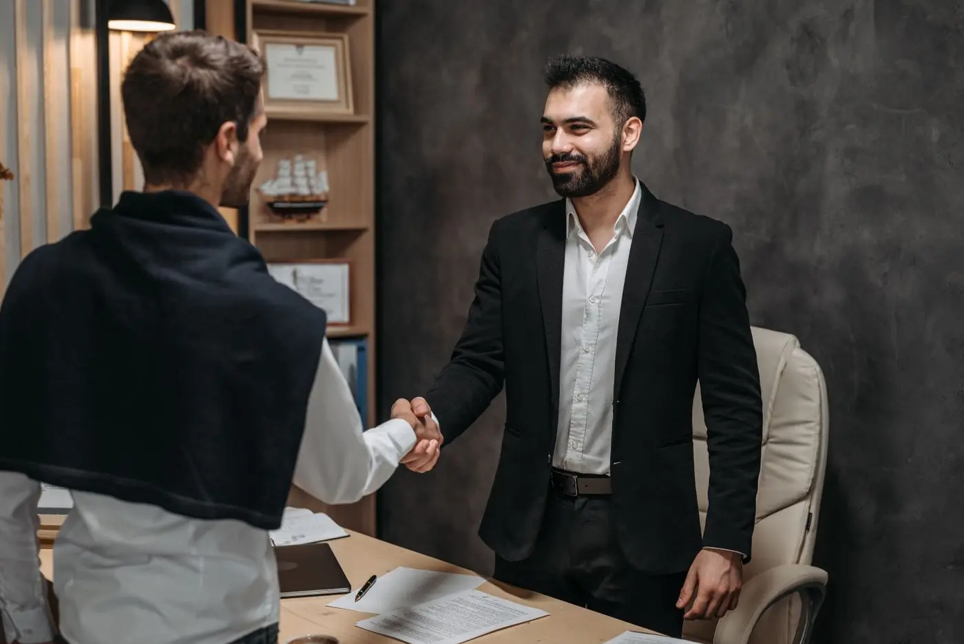 Business partners shaking hands over a signed agreement in an office